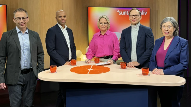 en grupp människor står bakom ett stort bord i en studio.