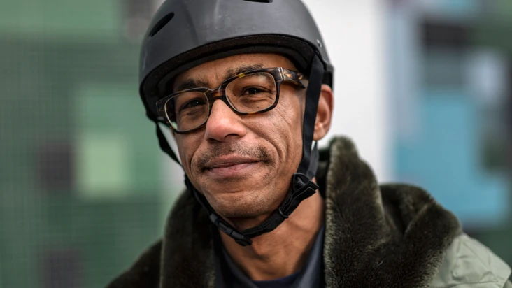 Porträtt av leende man i cykelhjälm fotad utomhus.