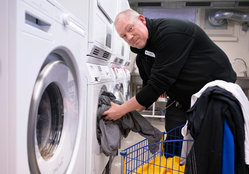 Mattias Cronesberry, anställd i Grums serviceteam, laddar en tvättmaskin med tvätt.