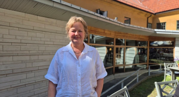 En kvinna står utomhus framför ett hus.