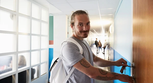 En man står i en korridor och låser en dörr.