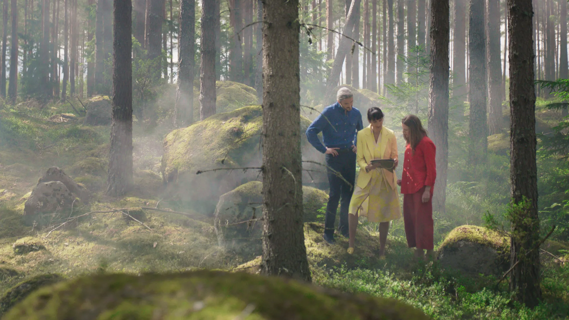 Chef, skyddsombud och medarbetare tittar på en karta i skogen.