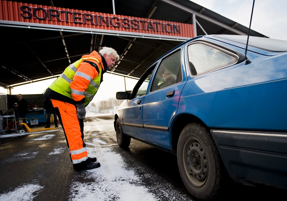 En person som jobbar på återvinningscentralen pratar med en bilförare.