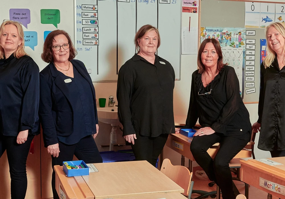 Skolan med Stockholms nöjdaste medarbetare. En personalgrupp poserar i ett klassrum.