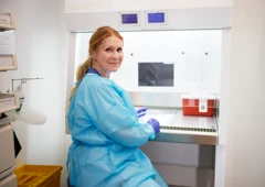 En kvinna i labbrock och handskar, tema arbetsanpassning.