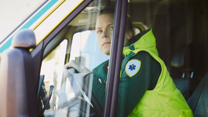 En kvinna som sitter i förarsätet på en ambulans.