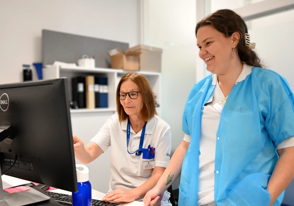 Två personer står i onkologens reception pratar om omtankesamtal.