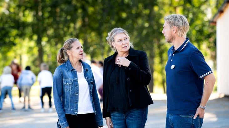 Tre personer st&aring;r p&aring; en skolg&aring;rd.