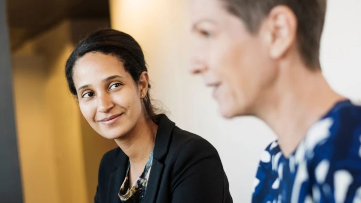 en kvinna tittar på en annan kvinna i kontorsmiljö.