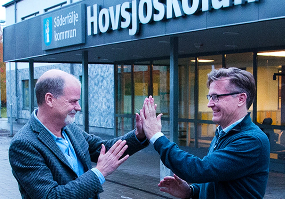 Två män gör high five utanför en byggnad.