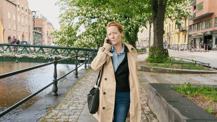En kvinna går längs en gata medan hon pratar i mobiltelefon.