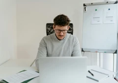 En man sitter framför en bärbar dator.