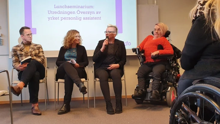 En grupp m&auml;nniskor som sitter i stolar och rullstolar framf&ouml;r en projektorduk.