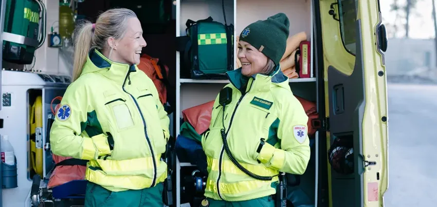 Tv&aring; kvinnor i ambulanskl&auml;der st&aring;r och pratar.