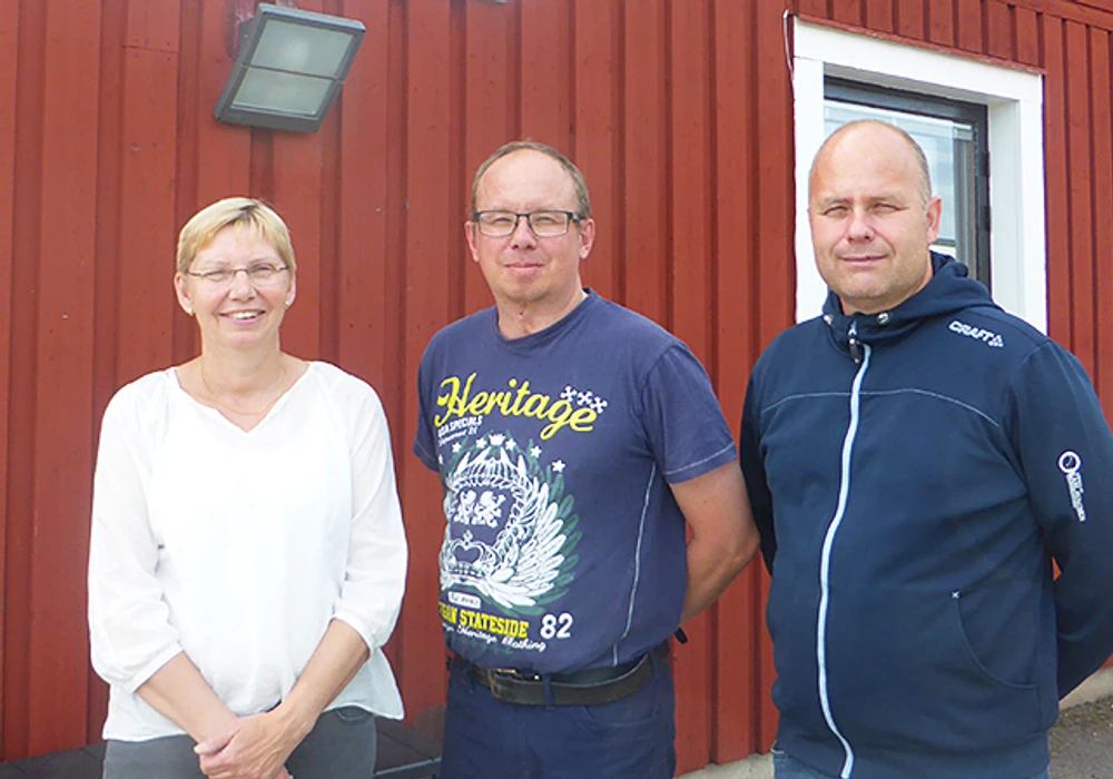 Tre personer står utomhus och tittar mot kameran.