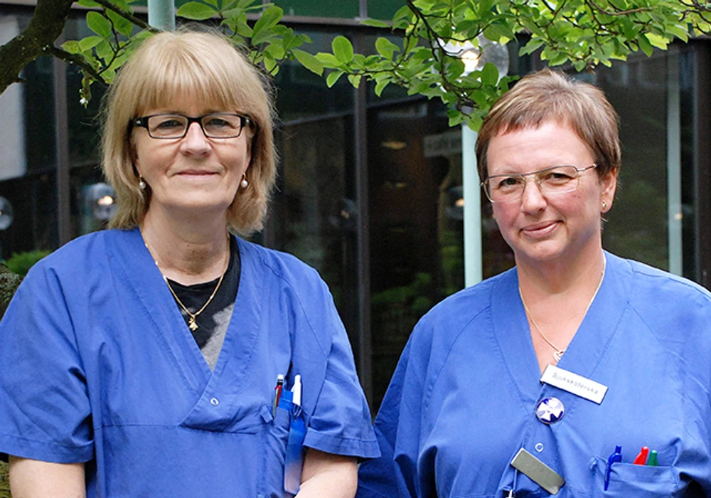Två kvinnor i blå vårdkläder.