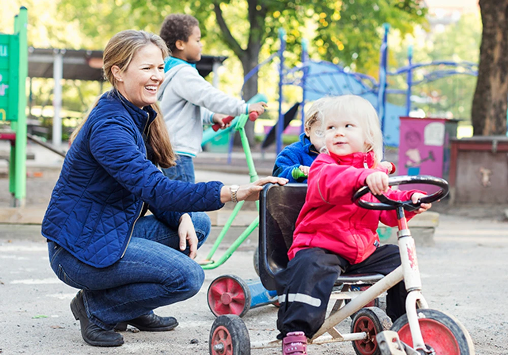 En vuxen och ett barn på en förskolegård.