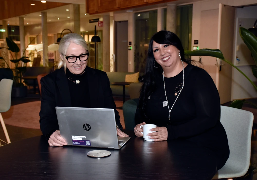 Chef och medarbetare arbetar vid bord med laptop.