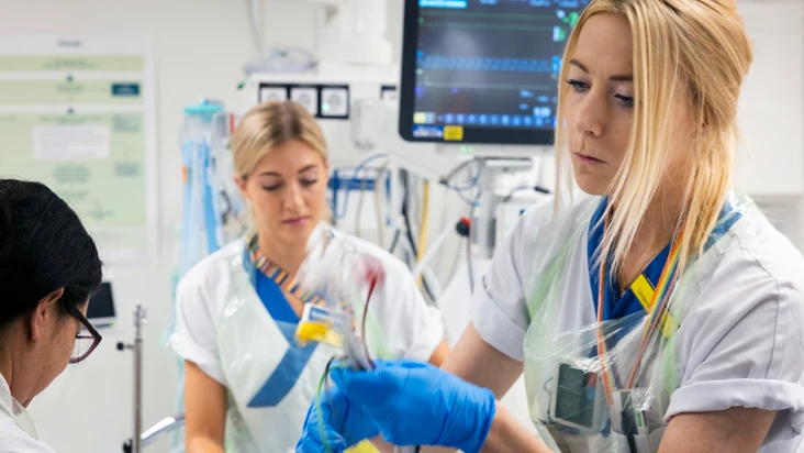 tv&aring; sjuksk&ouml;terskor h&aring;ller p&aring; att ordna med ett par sladdar i ett unders&ouml;kningsrum.