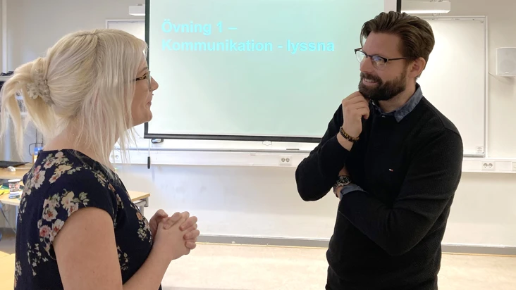 en kvinna och en man samtalar st&aring;ende framf&ouml;r en sk&auml;rm.