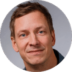 En man i jeansskjorta ler mot kameran.