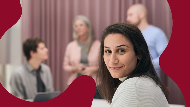 En kvinna som ler framf&ouml;r en grupp m&auml;nniskor.