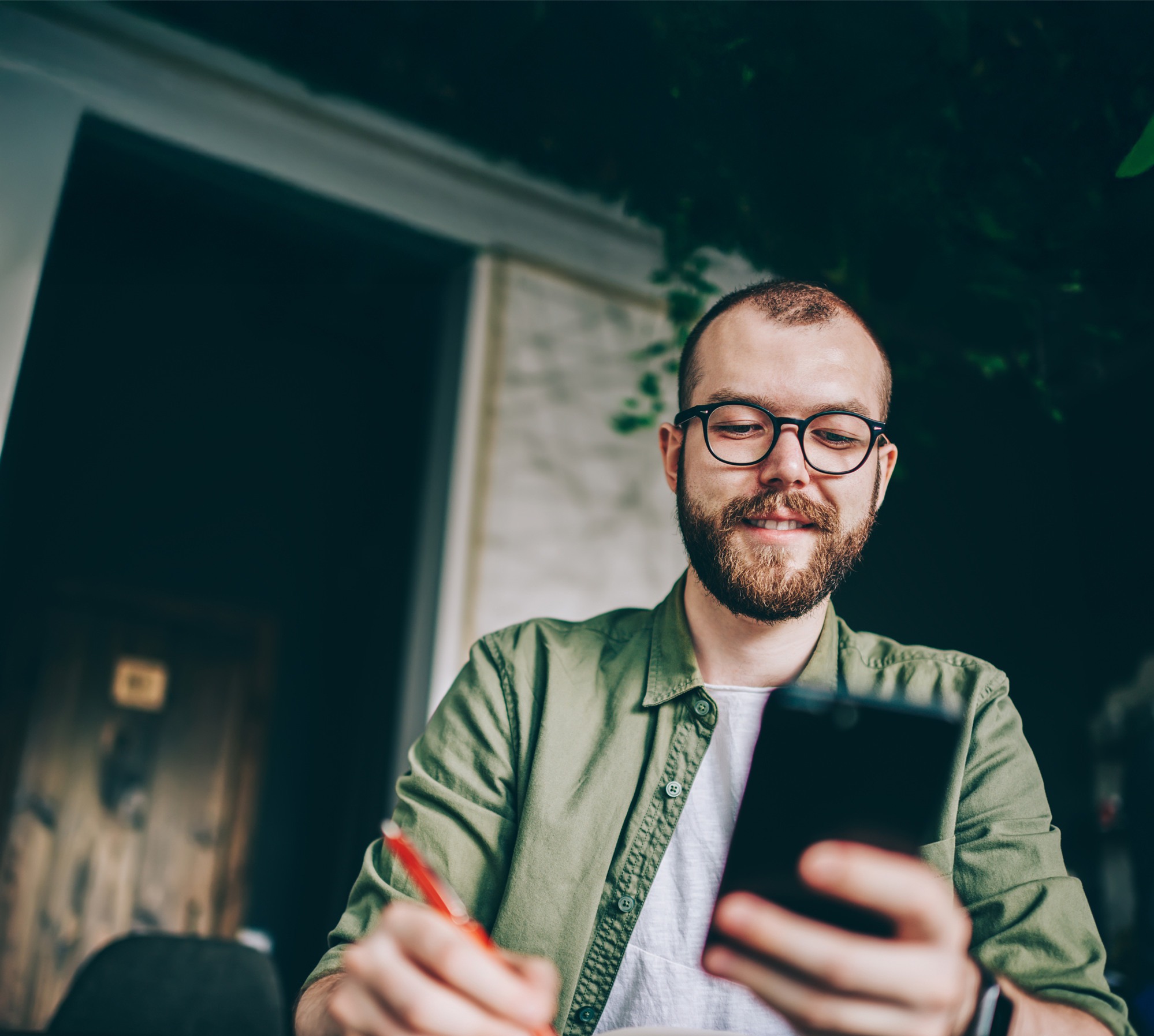 En man sitter vid ett bord och tittar p&aring; en mobiltelefon.