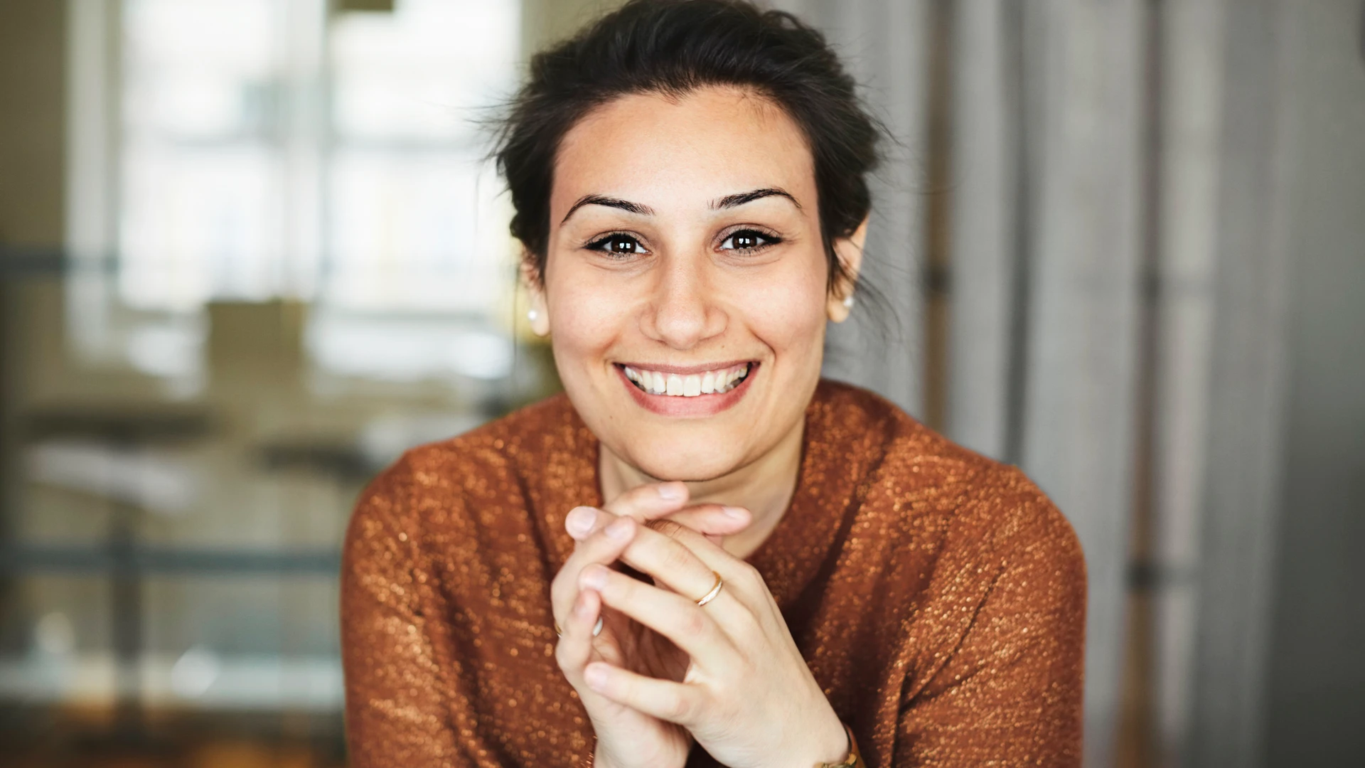 Leende kvinna med orange tr&ouml;ja tittar rakt fram.