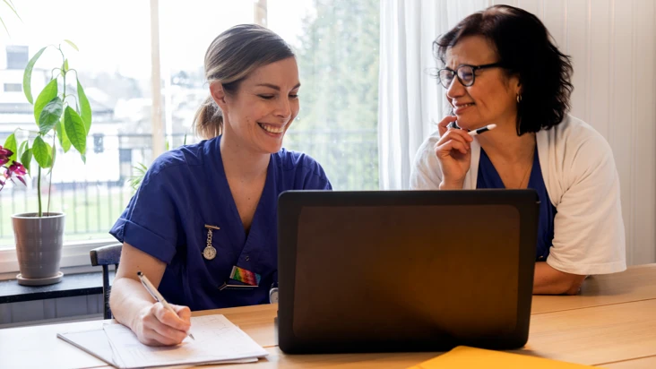 tv&aring; kvinnor sitter vid en dator och pratar med varandra.