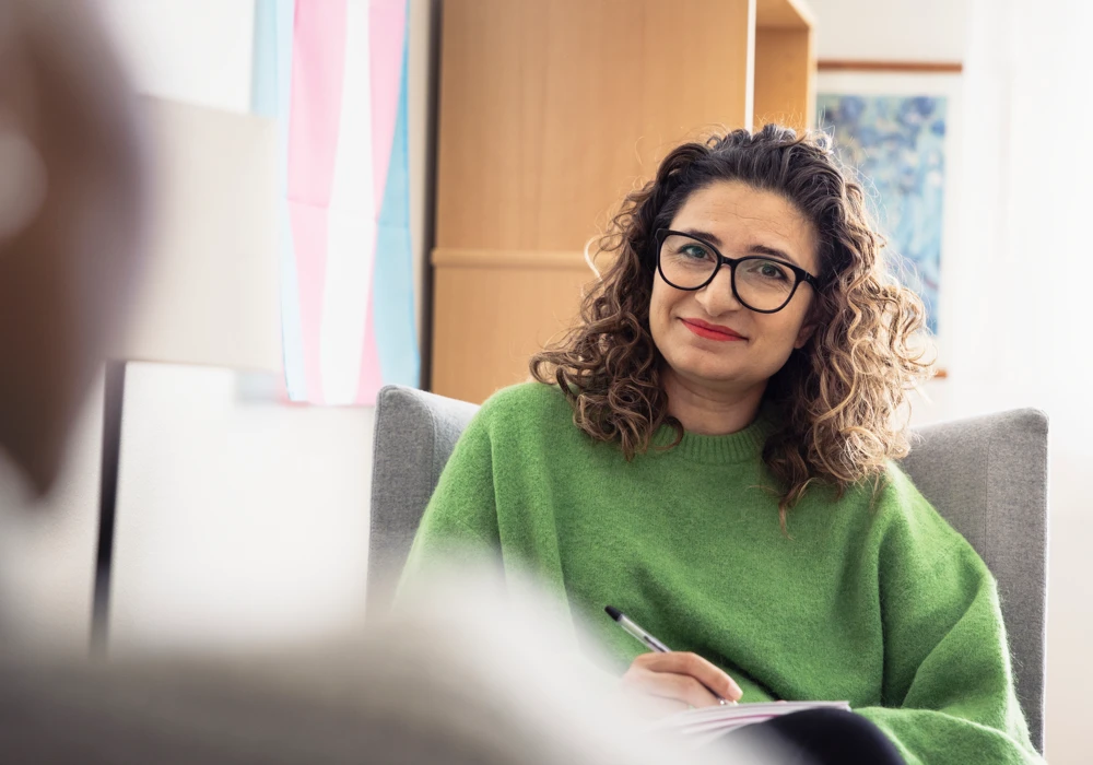Kvinna som sitter i fåtölj och lyssnar.