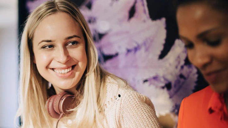 tv&aring; unga kvinnor intill varandra i inomhusmilj&ouml;, d&auml;r den ena har h&ouml;rlurar runt halsen.