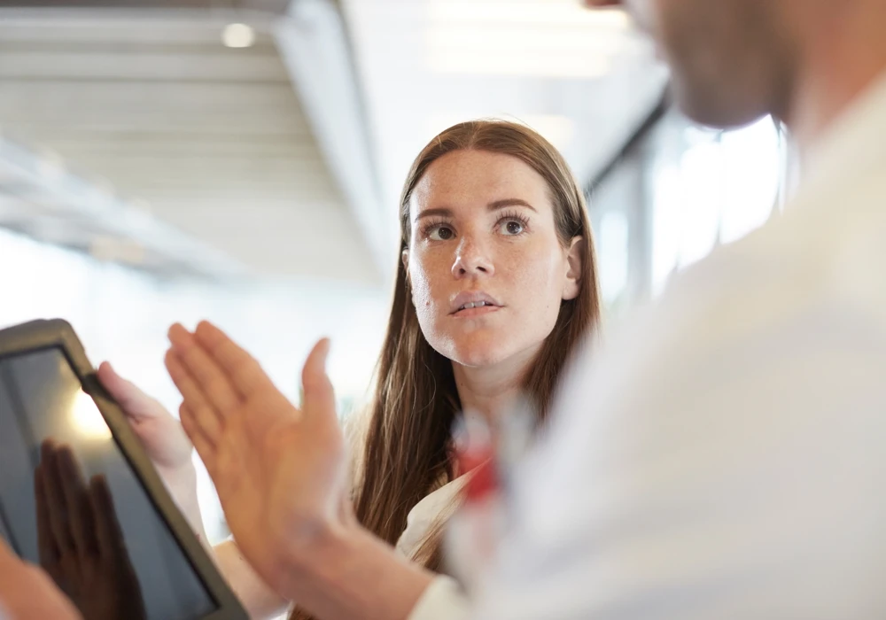 Ung vårdanställd tittar allvarligt på kollega. Höga emotionella krav är vanligt bland nya i yrket.