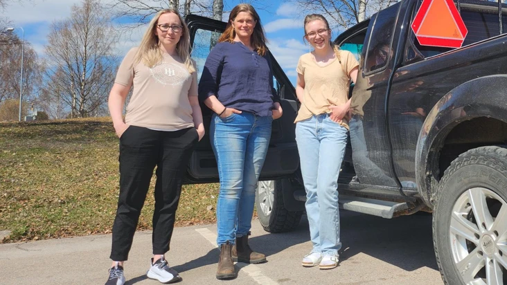 tre unga kvinnor framf&ouml;r en epa-traktor i v&aring;rsol.