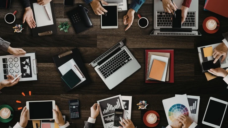 En grupp m&auml;nniskor som sitter vid ett bord och arbetar med b&auml;rbara datorer.