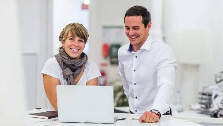 En kvinna och en man som tittar p&aring; en laptop tillsammans.