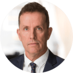 En man i kostym och slips tittar in i kameran.