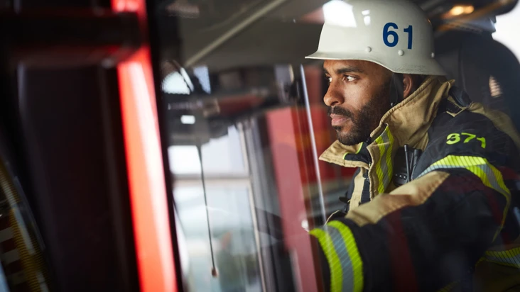 allvarlig brandman i i brandbil tittar fundersamt p&aring; n&aring;got utanf&ouml;r bilden.