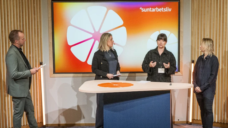 Fyra personer på en scen med Suntarbetslivs friskfaktorhjul och logga i bakgrunden.