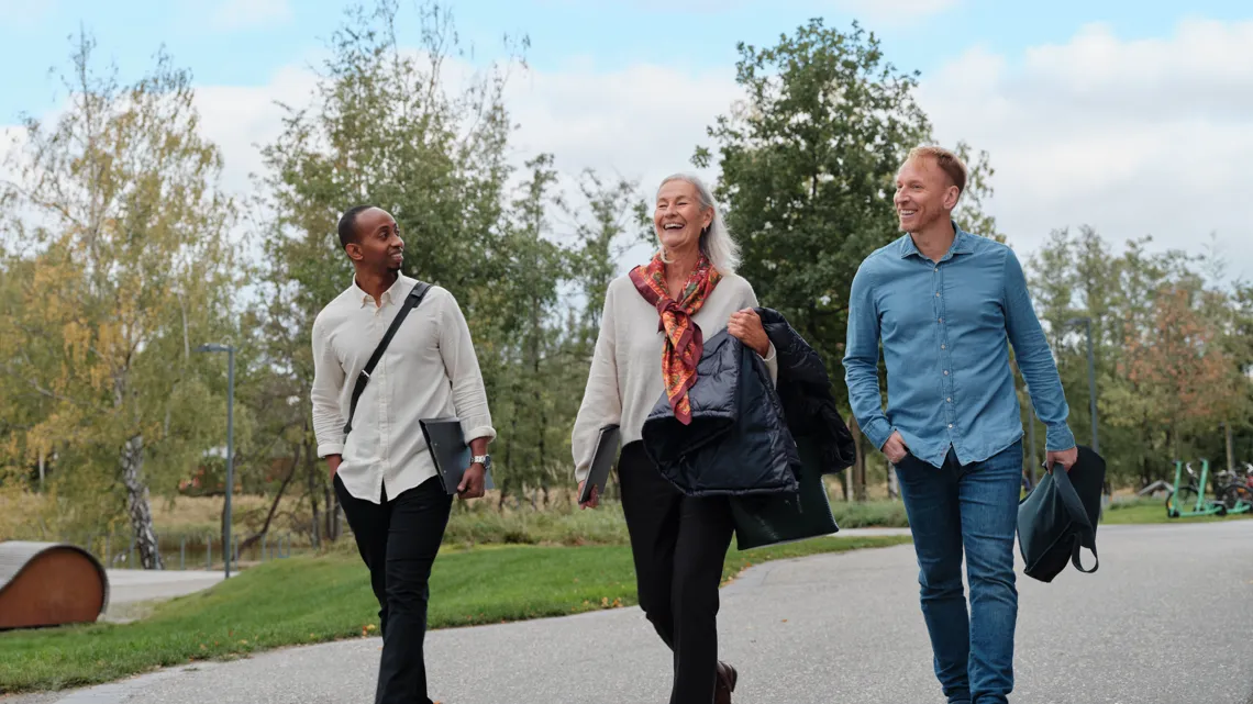 Tre kollegor går och pratar med varandra utomhus.