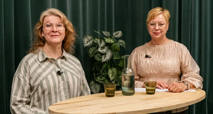 Två kvinnor som står bredvid varandra vid ett bord.