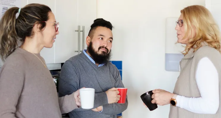 En grupp människor som står i ett kök och pratar.